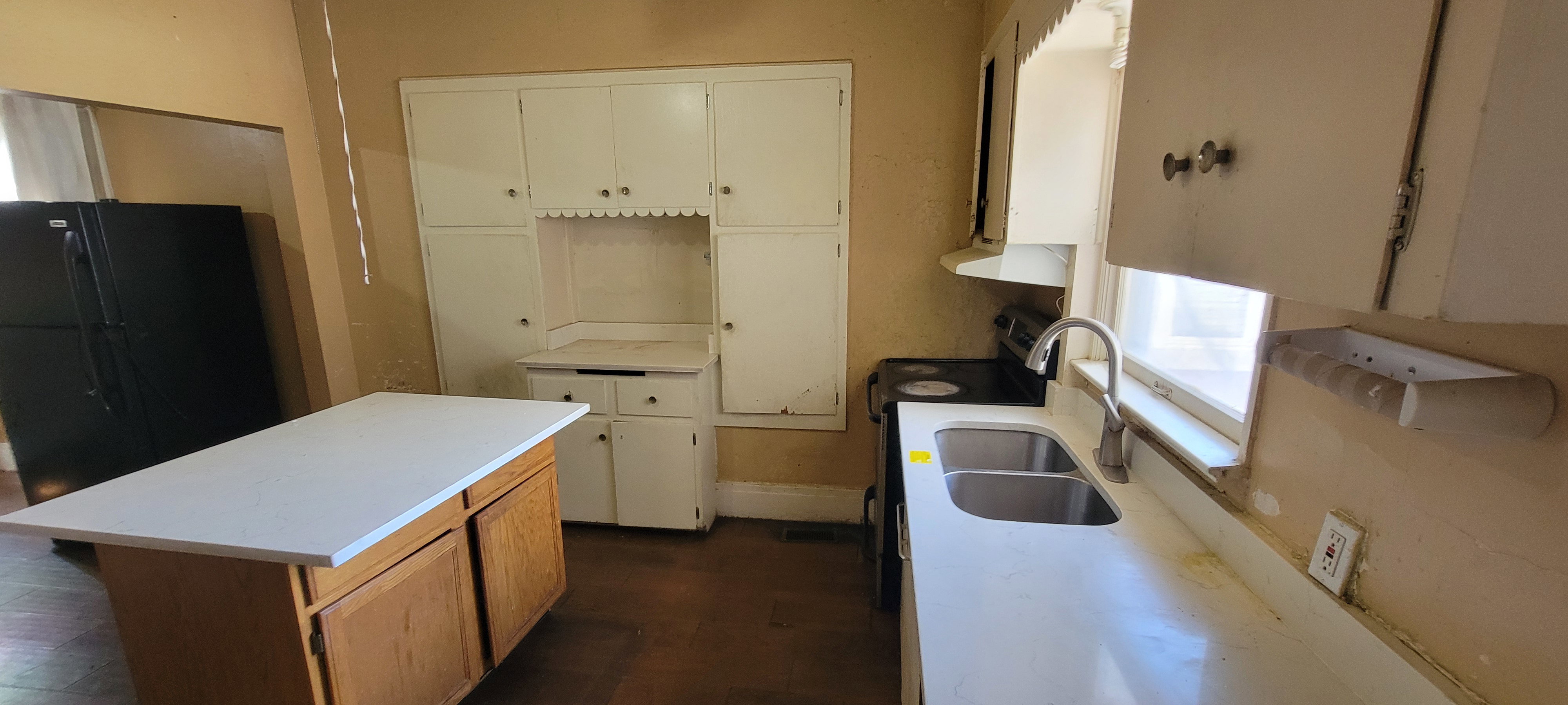 Kitchen featuring light countertops, a center island, electric range, dual tone cabinets, and freestanding refrigerator