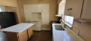 Kitchen featuring light countertops, a center island, electric range, dual tone cabinets, and freestanding refrigerator