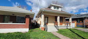 Bungalow-style home with a porch, a front lawn, brick siding, and roof with shingles