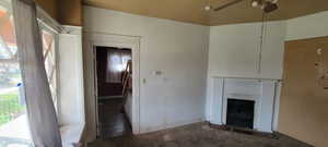 Unfurnished living room featuring dark carpet and ceiling fan