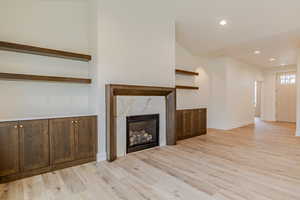 Unfurnished living room featuring light wood-style flooring, a premium fireplace, and recessed lighting