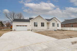 View of front of house featuring a garage, board and batten siding, driveway, and stone siding