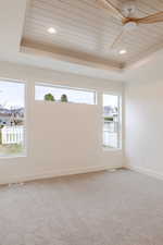 Carpeted empty room featuring ceiling fan, a wood tray ceiling, and recessed lighting