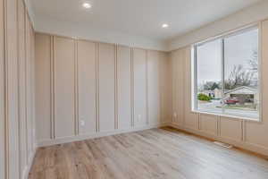 Empty room featuring light wood-style flooring, recessed lighting, and a decorative wall