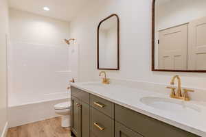 Bathroom with double vanity, light wood-style floors, bathing tub / shower combination, and recessed lighting