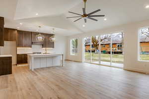 Dual tone kitchen with open floor plan, a center island with sink, dual tone cabinets, a ceiling fan, and light wood-style flooring