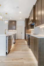 Kitchen featuring light wood-type flooring, electric range, a chandelier, and decorative backsplash