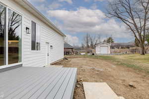 View of yard featuring a wooden deck, an outbuilding, and a garage