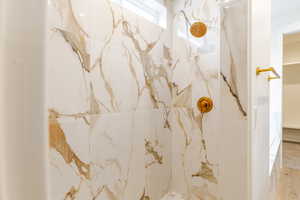 Full bath with a marble finish shower