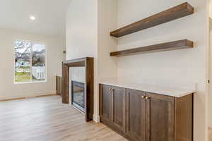 Unfurnished living room featuring light wood-type flooring, a glass covered fireplace, and recessed lighting