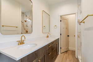 Bathroom with double vanity and light wood-style flooring