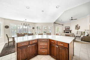Kitchen featuring a center island, open floor plan, light tile patterned floors, ceiling fan, and plenty of natural light