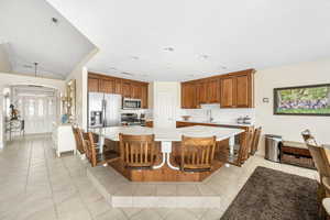 Kitchen featuring a kitchen breakfast bar, wood finish cabinets, a spacious island, light tile patterned floors, and recessed lighting