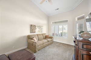 Sitting room with carpet flooring, a ceiling fan, and crown molding