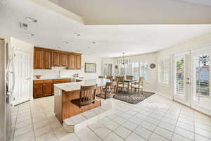 Kitchen with wood finish cabinets, light tile patterned flooring, a breakfast bar area, a textured ceiling, and stainless steel fridge