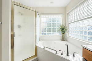 Bathroom featuring a shower stall, a jetted tub, and vanity