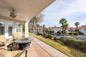 View of patio featuring a ceiling fan, an outdoor fire pit, a water view, french doors, and a residential view