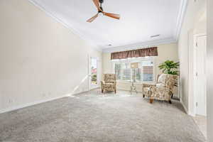 Living area featuring ornamental molding, a ceiling fan, light carpet, and arched walkways