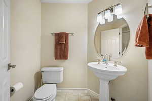 Half bathroom featuring toilet and light tile patterned floors