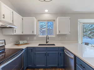 Kitchen with stainless steel appliances, two tone cabinets, light stone countertops, LVP Flooring