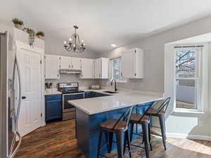 Kitchen with stainless steel appliances, two tone cabinets, light stone countertops, LVP Flooring, breakfast bar area,