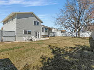 Back of house with a fully-fenced backyard, a gate, and a patio area