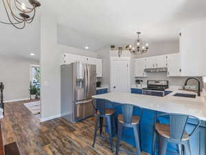 Kitchen with stainless steel appliances, two tone cabinets, light stone countertops, LVP Flooring, breakfast bar area,
