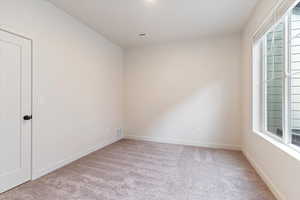 Spare room with light carpet and baseboards