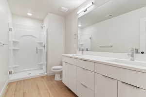 Full bath with a stall shower, double vanity, light wood-type flooring, and recessed lighting