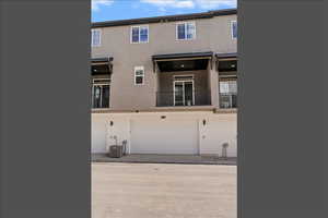 Back of house featuring a balcony, stucco siding, and an attached garage