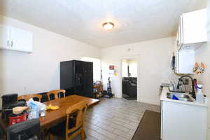 Kitchen featuring white cabinets, black fridge, a textured ceiling, stainless steel microwave, and stove