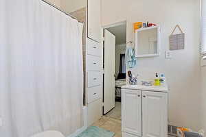 Full bath with vanity, shower / bath combo, and light tile patterned flooring
