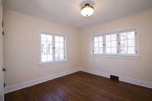 Spare room featuring dark wood finished floors and ornamental molding