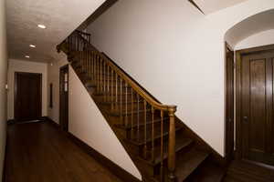 Staircase featuring wood finished floors, arched walkways, and recessed lighting