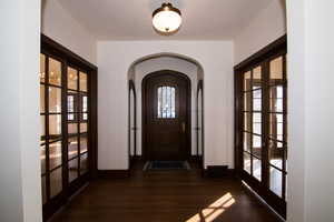 Foyer entrance with arched walkways, french doors, and dark wood finished floors