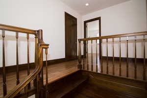 Staircase with wood finished floors and recessed lighting