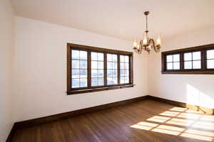 Empty room featuring hanging lights and dark wood-type flooring