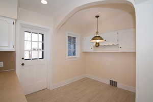 Unfurnished dining area with baseboards and light wood-type flooring