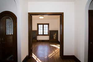 Corridor with arched walkways and dark wood-type flooring