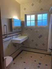 Bathroom with toilet and tile walls