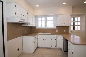 Kitchen with a peninsula, white cabinets, and recessed lighting