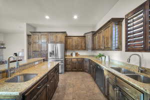 Kitchen with stainless steel fridge with ice dispenser, light stone counters, black dishwasher, recessed lighting, and dark wood finish cabinetry