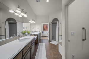 Ensuite bathroom with two vanities, stone tile flooring, and a stall shower