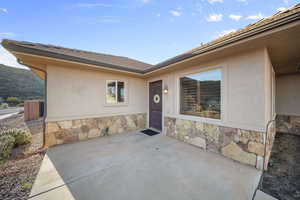 Doorway to property with stone siding, a patio area, and stucco siding