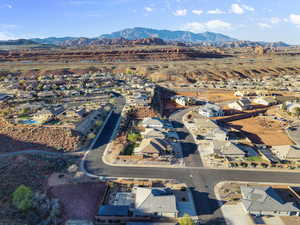 Aerial view of property and surrounding area featuring nearby suburban area and a mountain backdrop
