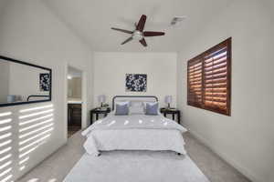 Carpeted bedroom with ensuite bath and ceiling fan