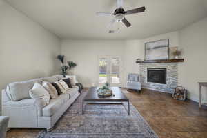 Living room with ceiling fan and a stone fireplace