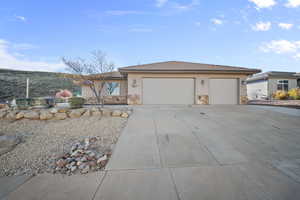 View of front of property with stucco siding, concrete driveway, a garage, and stone siding