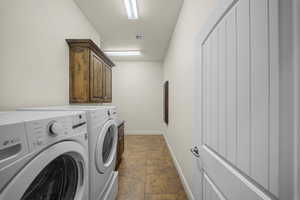 Laundry room with cabinet space, separate washer and dryer, and dark stone finish floors