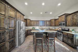 Kitchen featuring dark wood finish cabinets, a kitchen breakfast bar, stainless steel appliances, a kitchen island, and recessed lighting